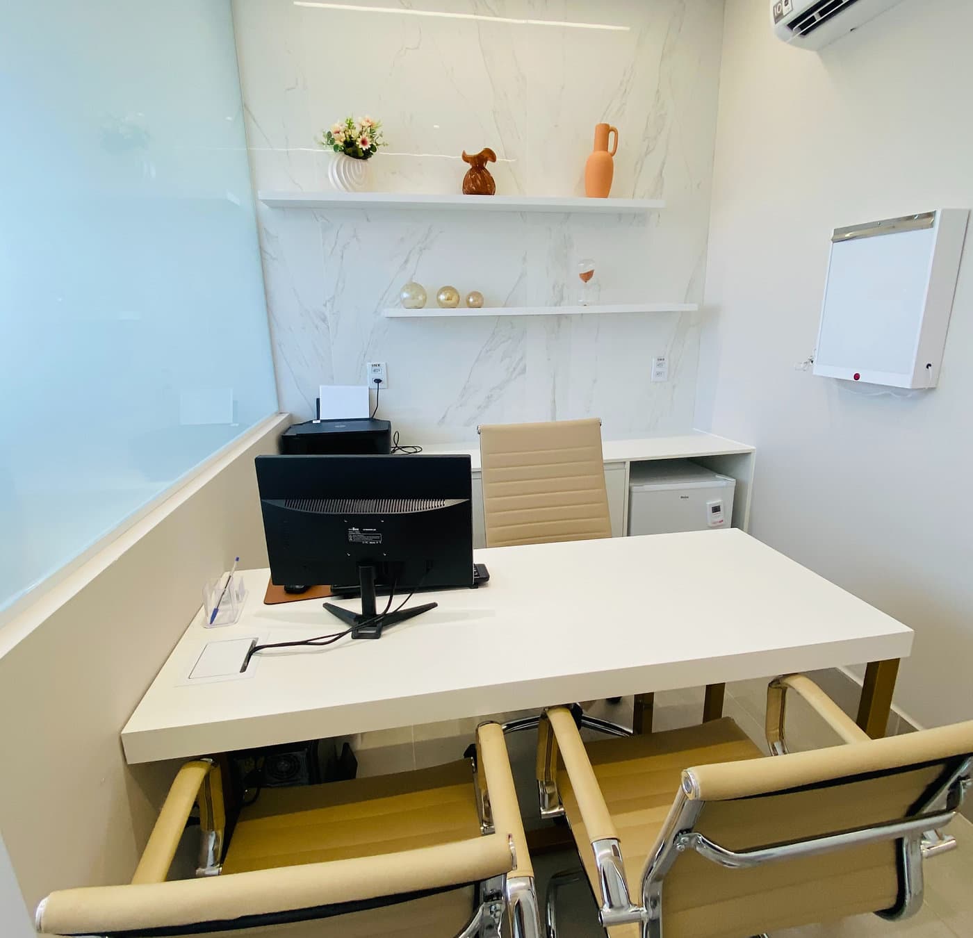 Consultório da unidade Lourdes do Instituto Hiraki: mesa branca, cadeiras, prateleiras e negatoscópio na parede