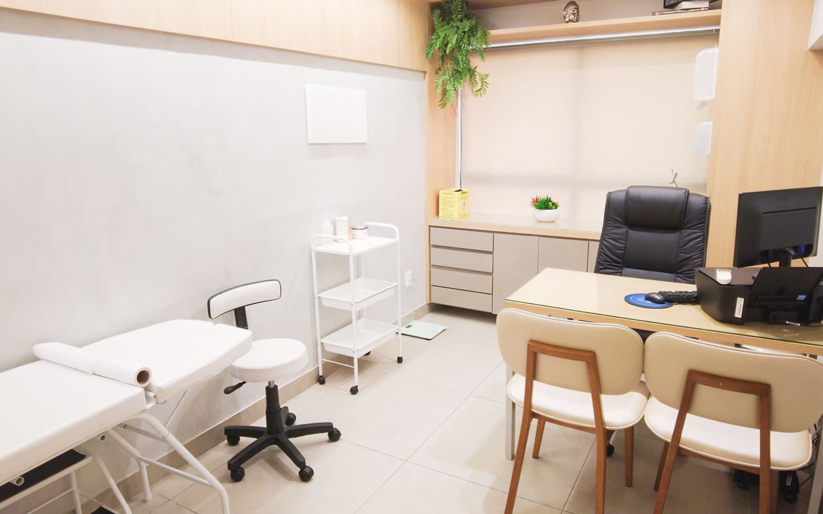 Sala de procedimentos da unidade Prado do Instituto Hiraki com maca, mocho, carrinho auxiliar e mesa de atendimento